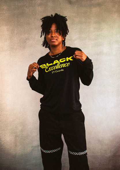 Person wearing a black sweatshirt with 'Black Excellence' text on a textured background