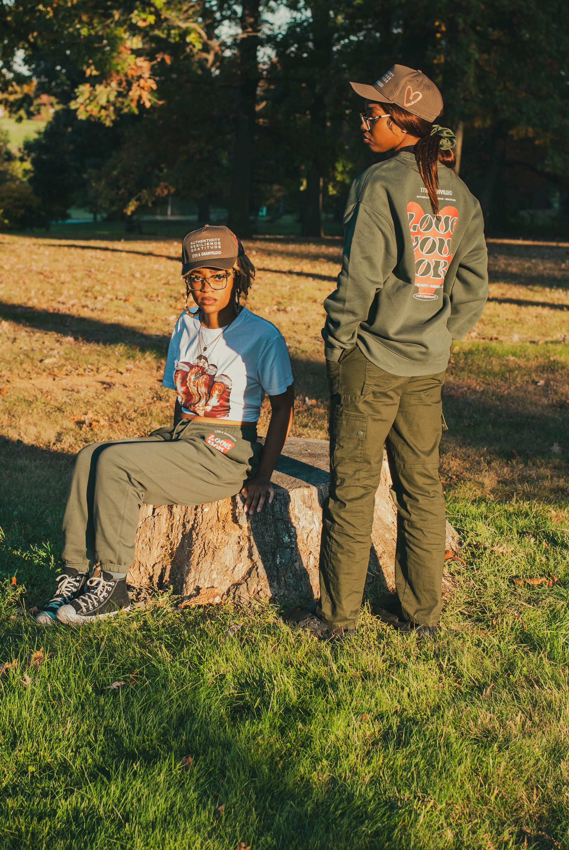Two models wearing Love You More sweatshirt and sweatpants with the ARG hat.